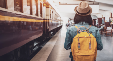 Eine junge Frau am Bahnhofsgleis neben einem Zug